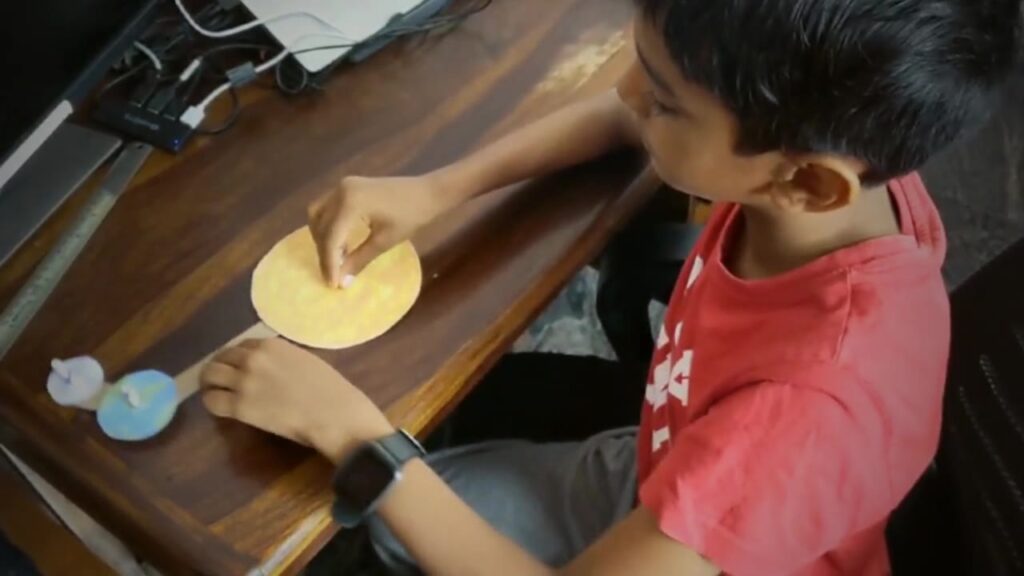 8 years old child exploring a model he made of the sun earth and moon